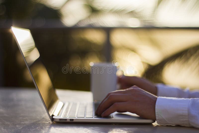 Mann mit Laptop und Tasse Kaffee bei Sonnenaufgang stockfotografie Mann mit Laptop und Tasse Kaffee bei Sonnenaufgang stockfotografie
