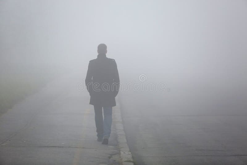 Mann mit seinem Rückseite gehend durch die Nebelstraße