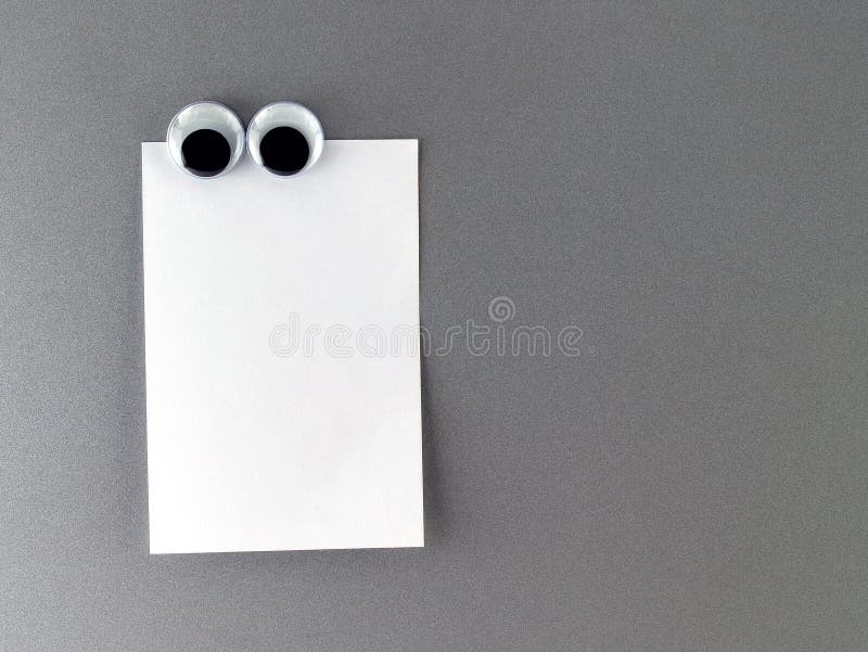 cute eyeball magnetic and notepaper for writing messages to communicate and reminder, close-up with copy space for text. cute eyeball magnetic and notepaper for writing messages to communicate and reminder, close-up with copy space for text