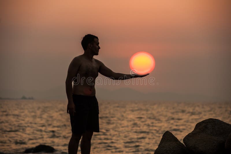 Male is engaged in fitness yoga exercise holding the Sun on the stone in Sunset. Male is engaged in fitness yoga exercise holding the Sun on the stone in Sunset.