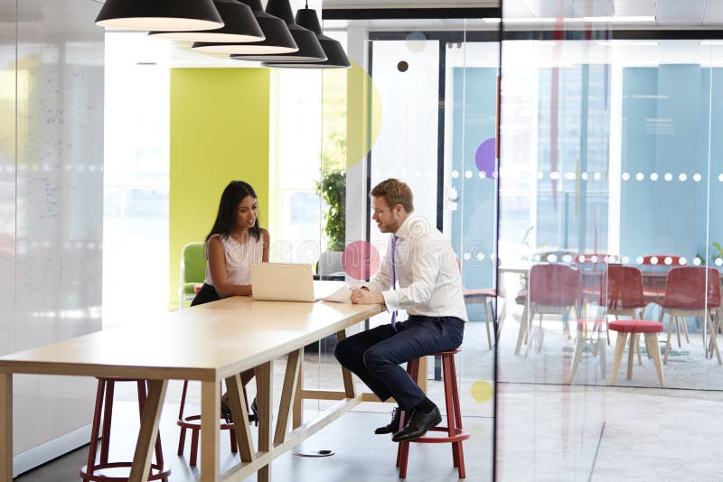 Mann und Frau, die eine informelle Sitzung bei der Arbeit haben lizenzfreies stockfoto Mann und Frau, die eine informelle Sitzung bei der Arbeit haben lizenzfreies stockfoto