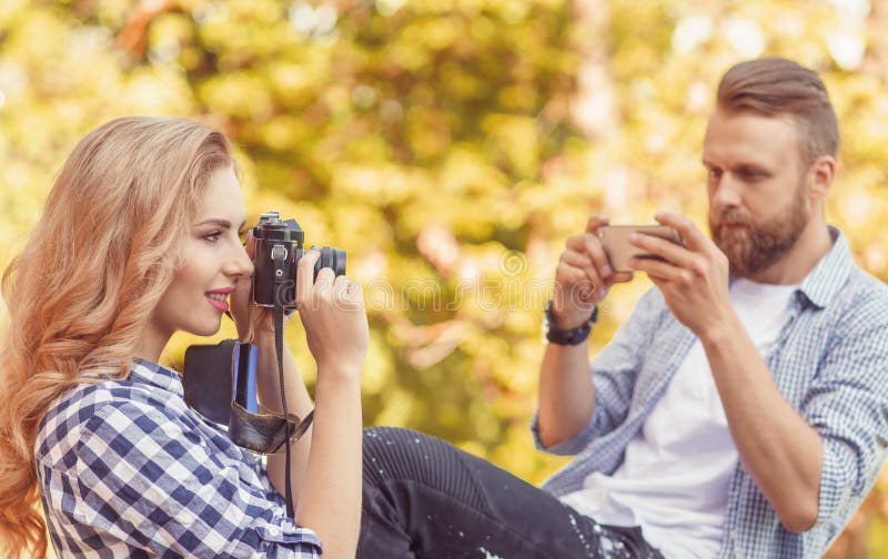 Mann und Frau, die Fotos mit einer Kamera und einem Smartphone im Herbstpark machen stockfoto Mann und Frau, die Fotos mit einer Kamera und einem Smartphone im Herbstpark machen stockfoto