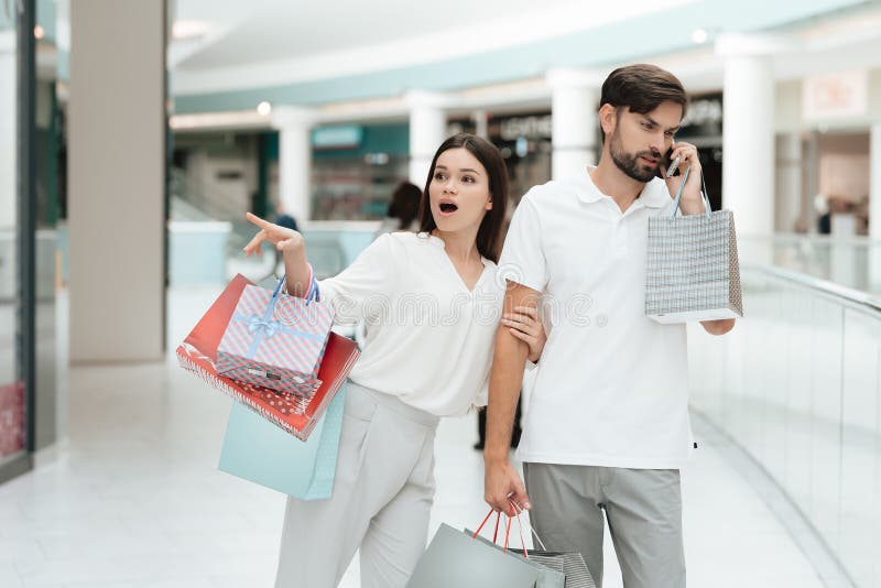 Mann und Frau gehen in Einkaufszentrum Frau möchte gehen zu speichern, aber Mann ist bemüht, am Telefon zu sprechen stockfotografie Mann und Frau gehen in Einkaufszentrum Frau möchte gehen zu speichern, aber Mann ist bemüht, am Telefon zu sprechen stockfotografie