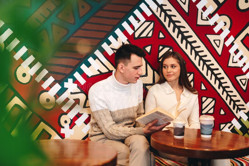 A man and a woman are seated at a wooden table. A man and a woman are seated at a wooden table