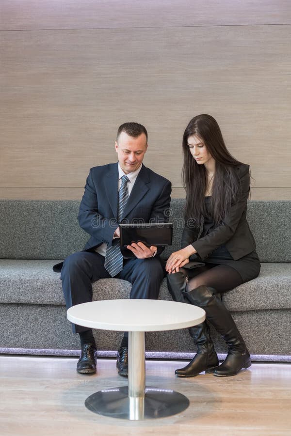 Mann und Mädchen in den Anzügen, die auf dem Sofa sitzen stockbild Mann und Mädchen in den Anzügen, die auf dem Sofa sitzen stockbild