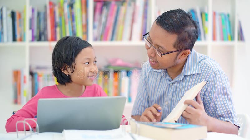 Mann unterrichtet kleines Mädchen, in der Bibliothek zu studieren