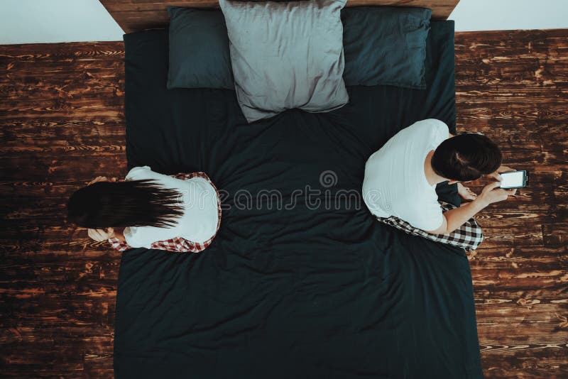 Mann verwendet Handy und Frau auf Bett lizenzfreie stockfotos Mann verwendet Handy und Frau auf Bett lizenzfreie stockfotos