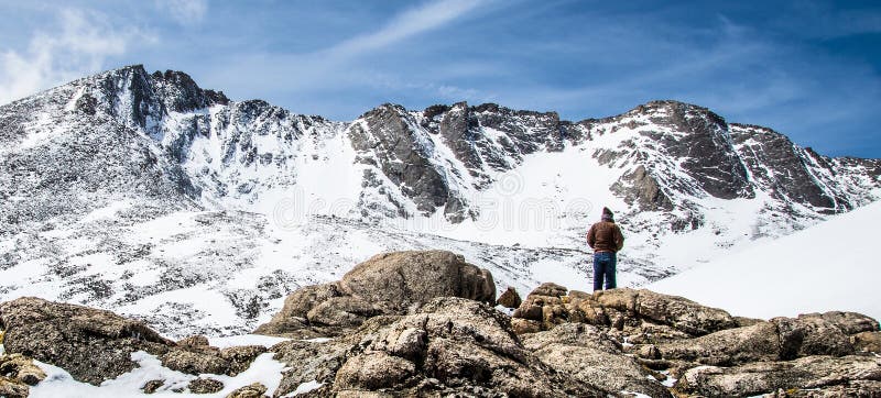 Man mountain hiker / backpacker looking at beautiful scenic view of the snow capped mountain peaks on the summit of Mt Evans. Mount Evans is one of the top travel vacation spots in the USA featuring the highest paved road in the northern hemisphere and is located near Denver Colorado. Man mountain hiker / backpacker looking at beautiful scenic view of the snow capped mountain peaks on the summit of Mt Evans. Mount Evans is one of the top travel vacation spots in the USA featuring the highest paved road in the northern hemisphere and is located near Denver Colorado.