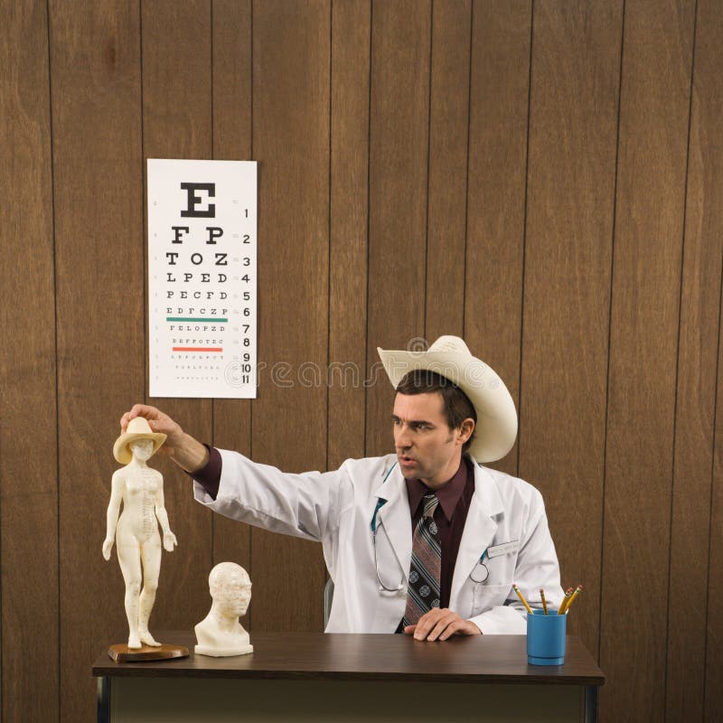 Mannelijke arts die cowboyhoed het spelen met beeldje draagt royalty-vrije stock fotografie Mannelijke arts die cowboyhoed het spelen met beeldje draagt royalty-vrije stock fotografie
