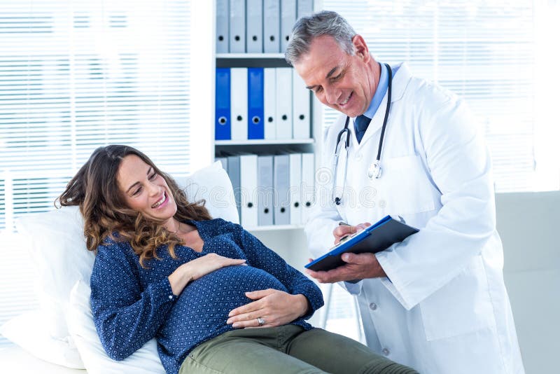 Mannelijke arts die document tonen aan zwangere vrouw in kliniek royalty-vrije stock afbeelding Mannelijke arts die document tonen aan zwangere vrouw in kliniek royalty-vrije stock afbeelding