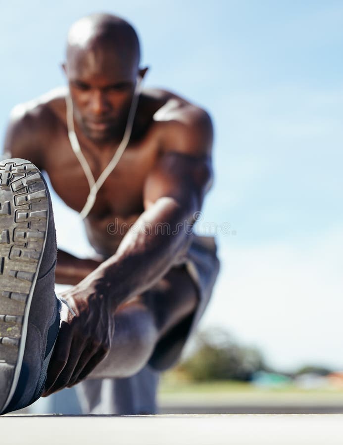 Male athlete stretching his leg muscles, with focus on leg. Muscular young man exercising outdoors. Male athlete stretching his leg muscles, with focus on leg. Muscular young man exercising outdoors.