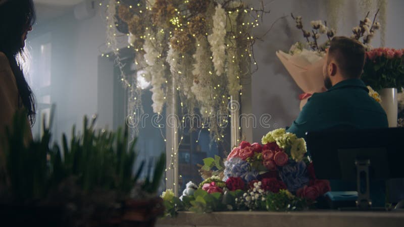 Mannelijke bloemist verkoper geeft verse bloemen aan vrouwelijke koper