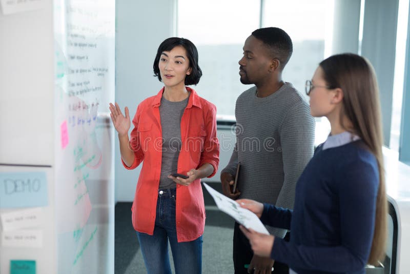 Mannelijke en vrouwelijke stafmedewerkers die op whiteboard bespreken royalty-vrije stock fotografie Mannelijke en vrouwelijke stafmedewerkers die op whiteboard bespreken royalty-vrije stock fotografie