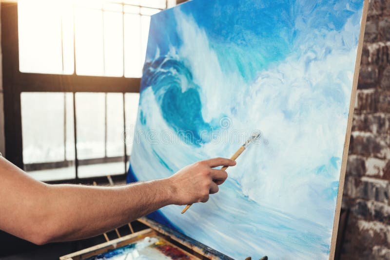 Mannelijke hand van het penseel van de kunstenaarsholding op achtergrond van canvas op schildersezel De professionele oceaangolf royalty-vrije stock fotografie Mannelijke hand van het penseel van de kunstenaarsholding op achtergrond van canvas op schildersezel De professionele oceaangolf royalty-vrije stock fotografie