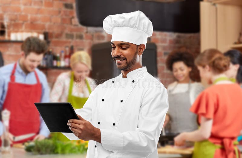 Mannelijke Indische chef-kok met tabletpc bij het koken van klasse royalty-vrije stock afbeelding Mannelijke Indische chef-kok met tabletpc bij het koken van klasse royalty-vrije stock afbeelding