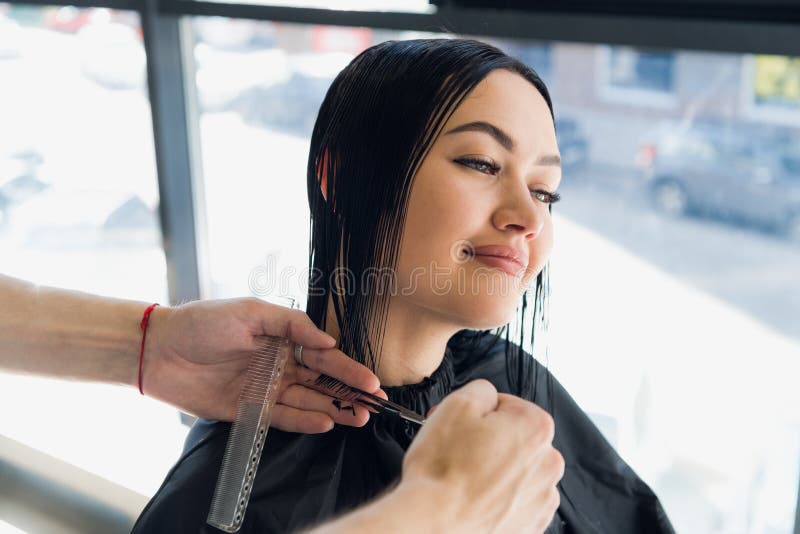 Mannelijke kapper die een kapsel voor een mooi donkerbruin meisje in professionele herenkapper maken stock fotografie Mannelijke kapper die een kapsel voor een mooi donkerbruin meisje in professionele herenkapper maken stock fotografie