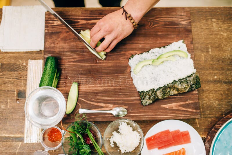 Mannelijke kokhanden die sushibroodjes, zeevruchten maken royalty-vrije stock afbeeldingen Mannelijke kokhanden die sushibroodjes, zeevruchten maken royalty-vrije stock afbeeldingen