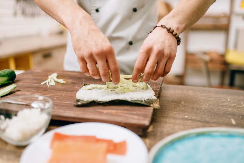 Mannelijke kokhanden die sushibroodjes, zeevruchten maken royalty-vrije stock afbeeldingen Mannelijke kokhanden die sushibroodjes, zeevruchten maken royalty-vrije stock afbeeldingen