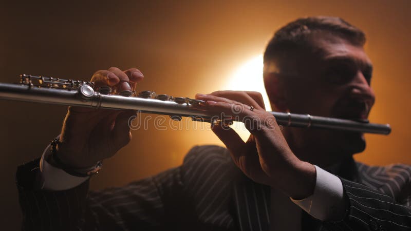 Mannelijke muzikant speelt fluit op het podium in spotlight