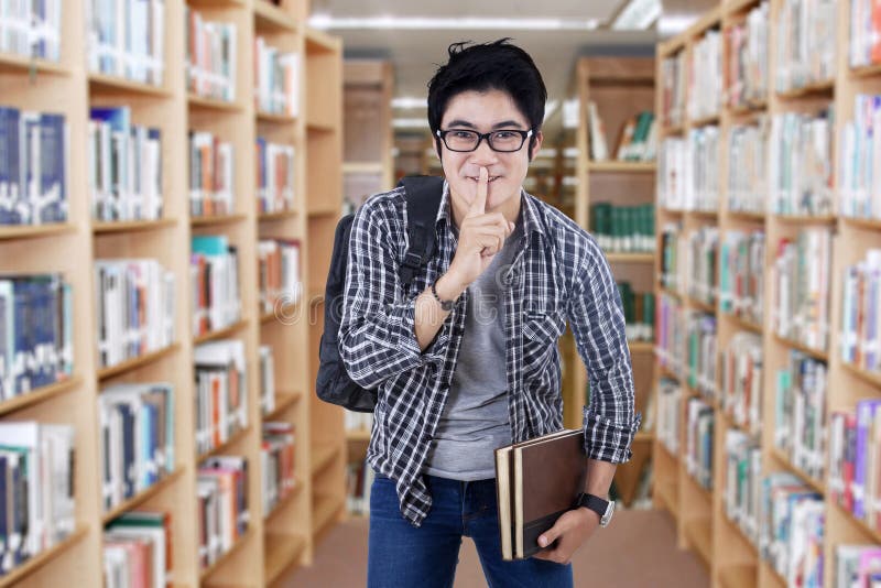 Mannelijke student die stilteteken maken stock afbeeldingen Mannelijke student die stilteteken maken stock afbeeldingen