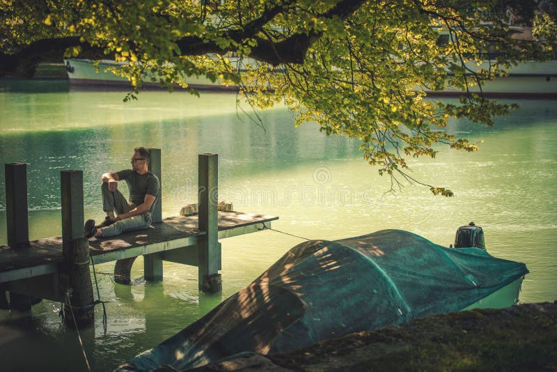 Mannen genieten van de zomertijd op de rivierpier