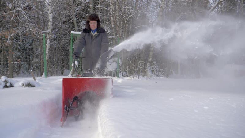 Mannen gör ren snö med bakgrund för maskinen för snöborttagning Forest In Winter