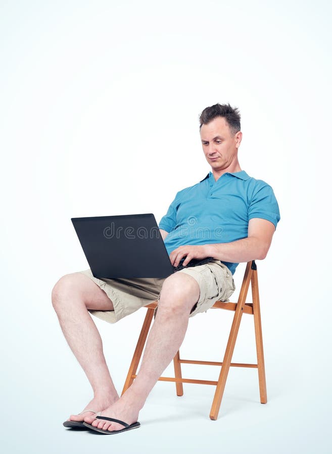 Mannen i sommarkläder sitter på en stol som skriver på en bärbar dator Ljus bakgrund Begrepp av arbete på semester royaltyfri fotografi Mannen i sommarkläder sitter på en stol som skriver på en bärbar dator Ljus bakgrund Begrepp av arbete på semester royaltyfri fotografi