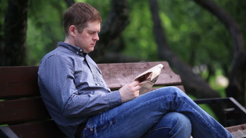 Mannen läser tidningen på bänk i parkera 2