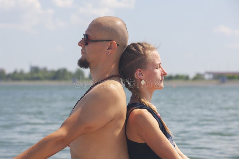 Mannen och gravida kvinnan g?r yoga p? stranden arkivfoton Mannen och gravida kvinnan g?r yoga p? stranden arkivfoton