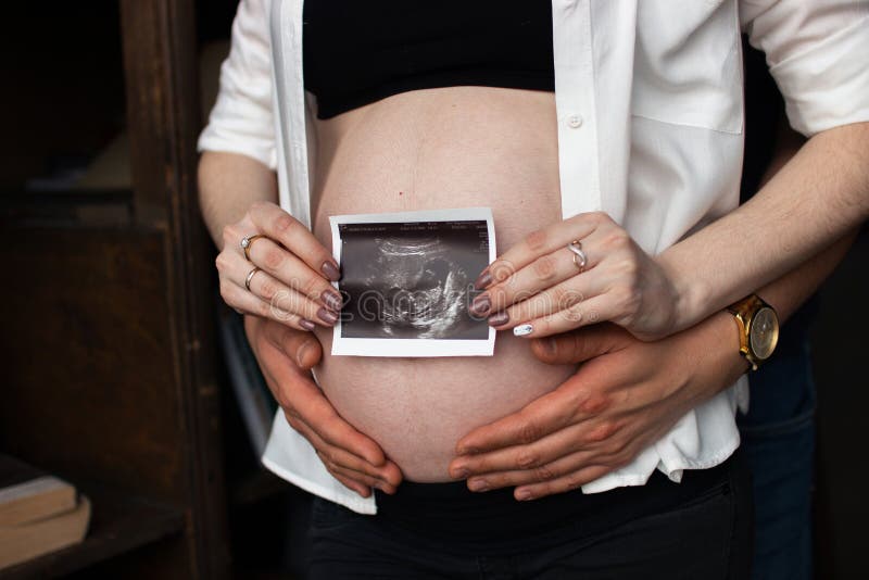 Mannen satte hans hand på hennes buk med uzibarnet royaltyfri foto Mannen satte hans hand på hennes buk med uzibarnet royaltyfri foto