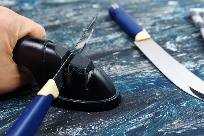 Sharpening a knife. Close-up of a man using a sharpener to sharpen a knife blade. Sharpening a knife. Close-up of a man using a sharpener to sharpen a knife blade