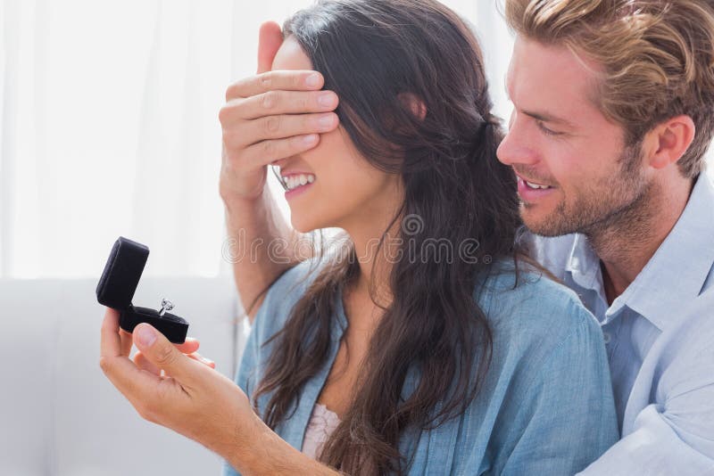 Mannen som döljer hans wifes, synar för att erbjuda henne en förlovningsring fotografering för bildbyråer Mannen som döljer hans wifes, synar för att erbjuda henne en förlovningsring fotografering för bildbyråer