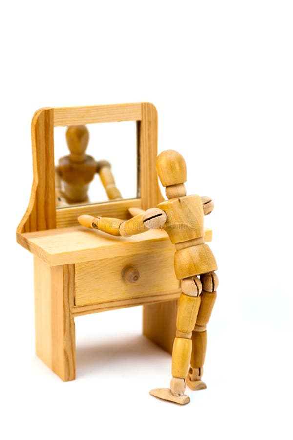 Wooden artist's drawning mannequin looking at self in a vanity dresser mirror. White isolation. Concepts could consist of looking at oneself, vanity; concerned or worries over appearance; watching oneself. Wooden artist's drawning mannequin looking at self in a vanity dresser mirror. White isolation. Concepts could consist of looking at oneself, vanity; concerned or worries over appearance; watching oneself