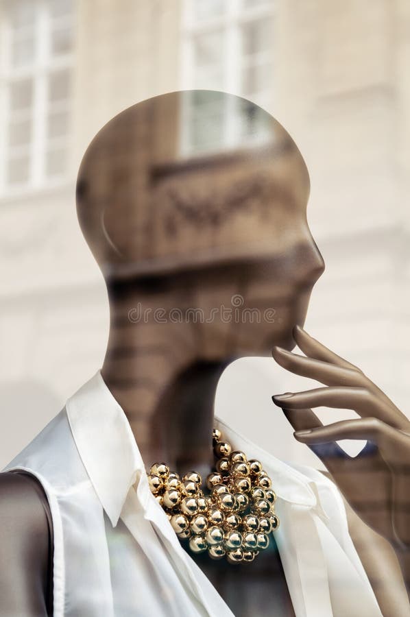 Portrait of female mannequin in store window. Reflections of the surrounding buildings, toned image.