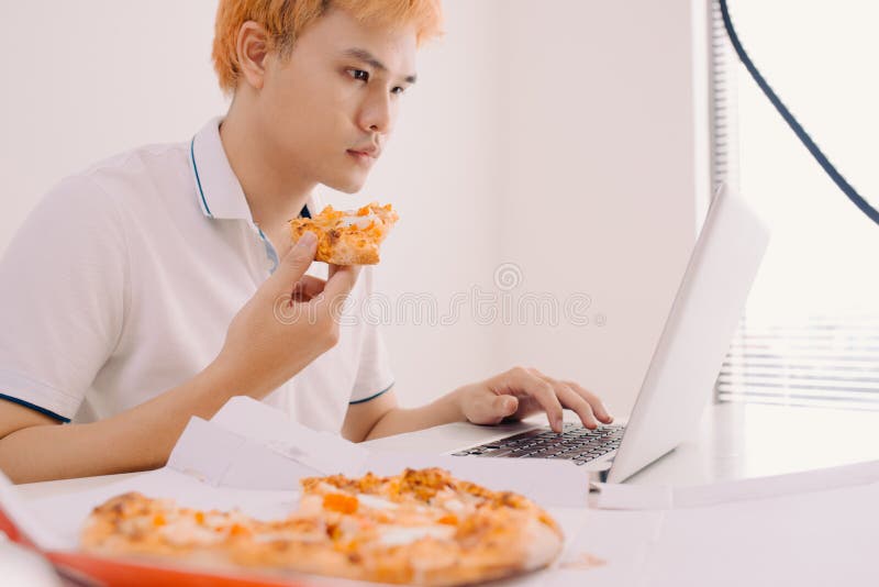 Mannetje die freelancer pizza eten terwijl thuis het werken van bureau royalty-vrije stock afbeeldingen Mannetje die freelancer pizza eten terwijl thuis het werken van bureau royalty-vrije stock afbeeldingen