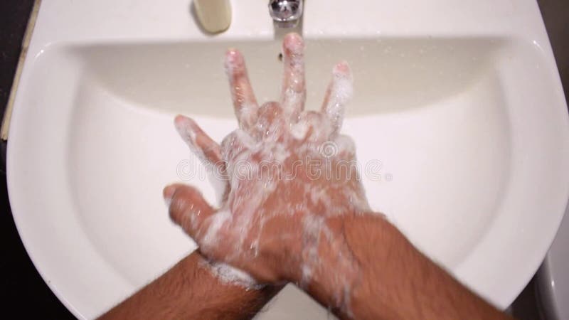 Mannetjeshanden wassen in een gootsteen met een stevige vloeibare handwas om coronavirus te voorkomen