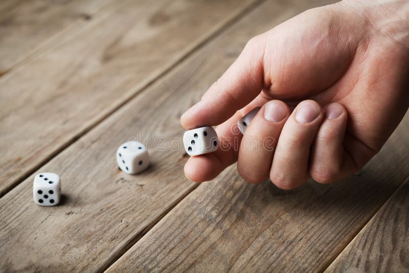 Mannhandwerfende weiße Würfel auf Holztisch Spielende Geräte Glücksspiel Konzept