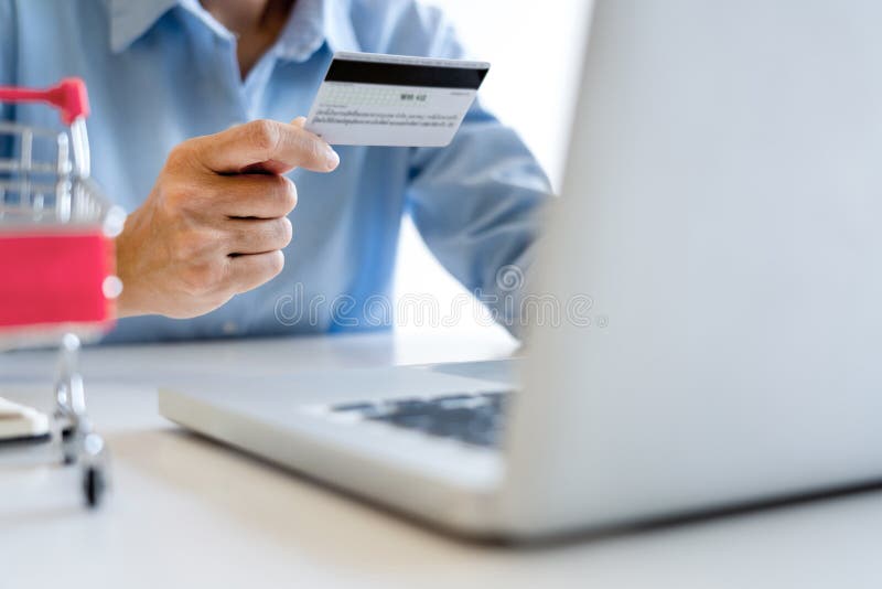 Mannholdingkreditkarte in der Hand und hereinkommender Sicherheitscode unter Verwendung des intelligenten Telefons auf Laptoptast lizenzfreie stockfotos Mannholdingkreditkarte in der Hand und hereinkommender Sicherheitscode unter Verwendung des intelligenten Telefons auf Laptoptast lizenzfreie stockfotos