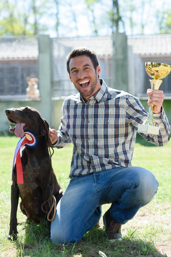 Mannholdingtrophäe mit Hund auf Seite stockbilder Mannholdingtrophäe mit Hund auf Seite stockbilder