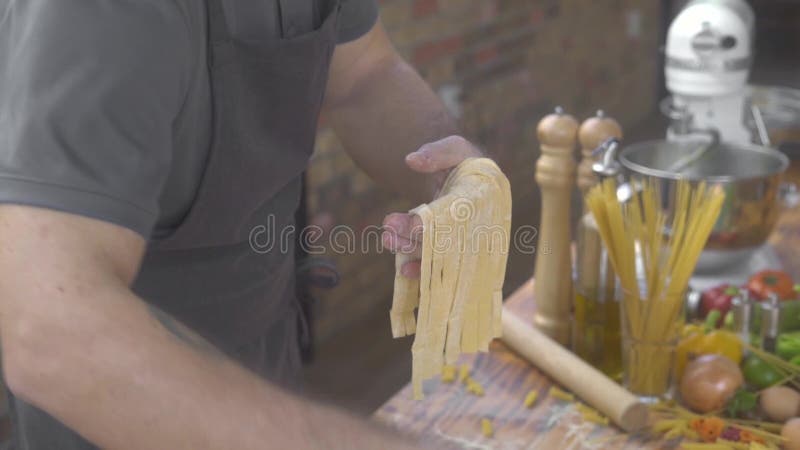 Mannkoch, der frische italienische Teigwaren auf Hauptk?che auf Nahrungsmittelhintergrund macht Chefkoch, der vorbei handgemachte