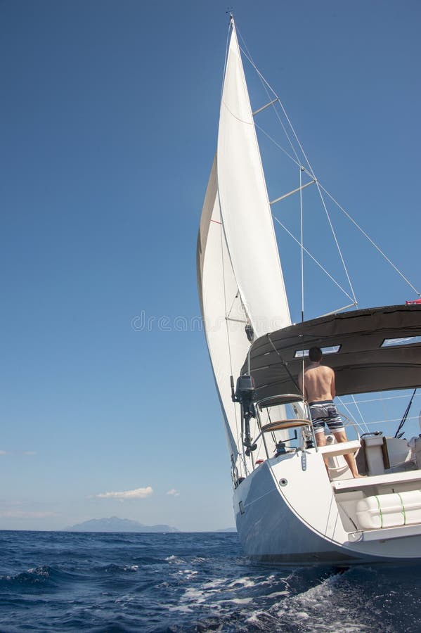 Mannsegeln in Richtung zu einer Insel in Kroatien stockfoto Mannsegeln in Richtung zu einer Insel in Kroatien stockfoto