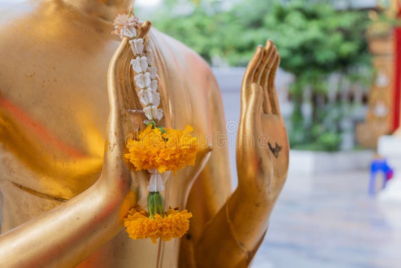 Mano alta vicina della ghirlanda del fiore della tenuta di colore dell'oro della statua di Buddha in tempio fotografia stock Mano alta vicina della ghirlanda del fiore della tenuta di colore dell'oro della statua di Buddha in tempio fotografia stock