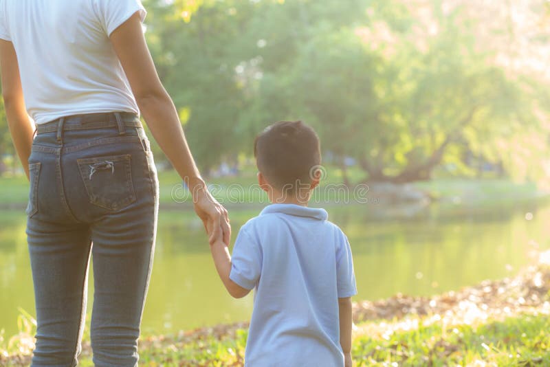 Mano asi?tica de la tenencia de la madre o del padre y del hijo con amor junto en exterior del verano en el parque fotos de archivo libres de regalías Mano asi?tica de la tenencia de la madre o del padre y del hijo con amor junto en exterior del verano en el parque fotos de archivo libres de regalías
