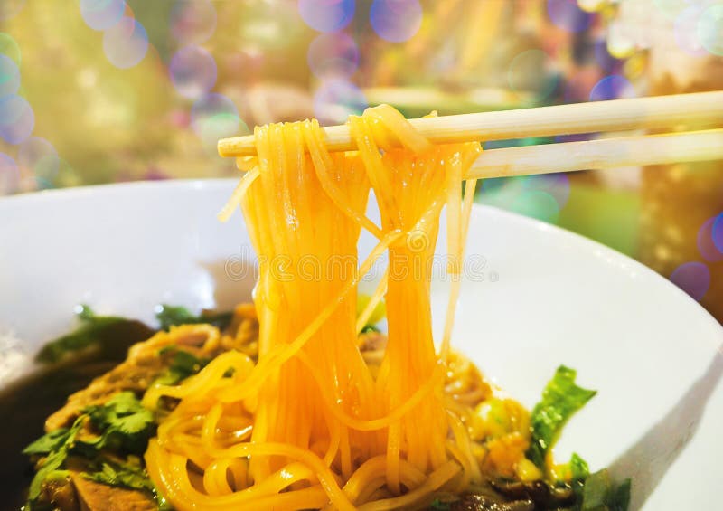 Mano che prende noodless piccolo di cottura a vapore saporito con l'erba in ciotola sul fondo naturale della luce del bokeh Mines immagine stock libera da diritti Mano che prende noodless piccolo di cottura a vapore saporito con l'erba in ciotola sul fondo naturale della luce del bokeh Mines immagine stock libera da diritti