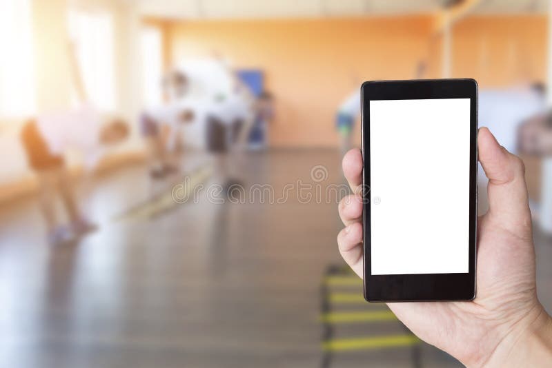 Mano con cellulare sullo sfondo di persone impegnate in un centro fitness Concetto dell'app per telefono palestra e palestra, spa fotografia stock Mano con cellulare sullo sfondo di persone impegnate in un centro fitness Concetto dell'app per telefono palestra e palestra, spa fotografia stock