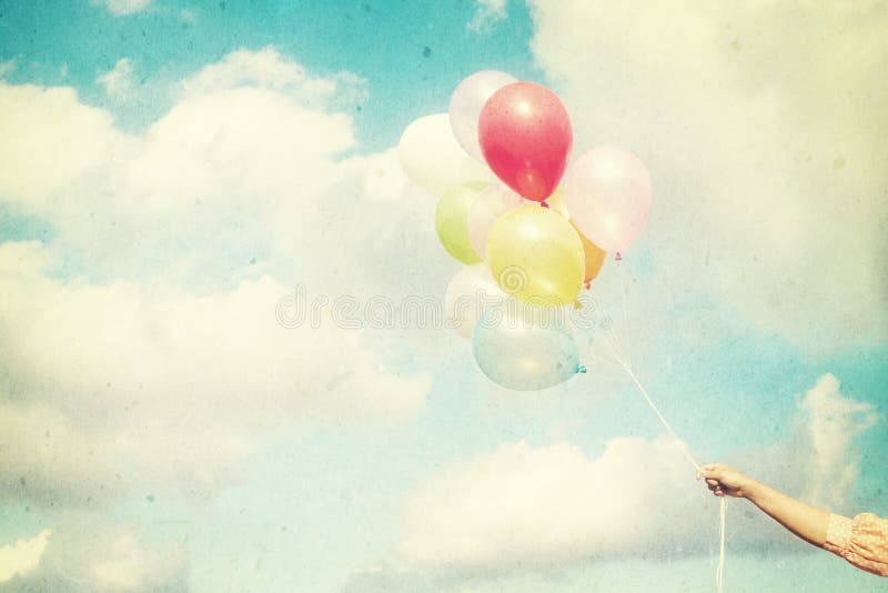 Girl hand holding multicolored balloons done with a retro vintage filter effect, concept of happy birth day in summer and wedding honeymoon party Vintage color tone paper texture. Girl hand holding multicolored balloons done with a retro vintage filter effect, concept of happy birth day in summer and wedding honeymoon party Vintage color tone paper texture