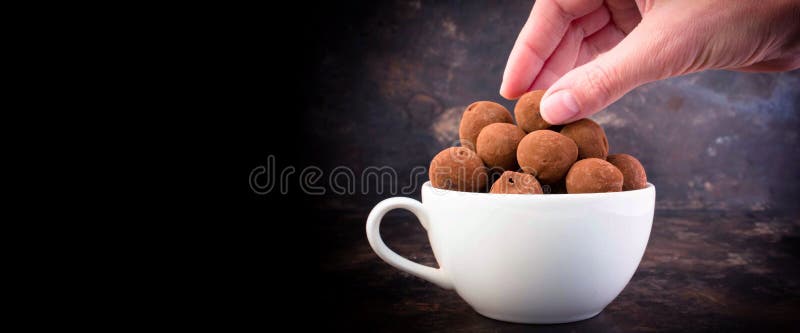 MANO DE LA MUJER DE LA BANDERA QUE SOSTIENE UNA TRUFA DE CHOCOLATE SABROSA fotografía de archivo libre de regalías MANO DE LA MUJER DE LA BANDERA QUE SOSTIENE UNA TRUFA DE CHOCOLATE SABROSA fotografía de archivo libre de regalías