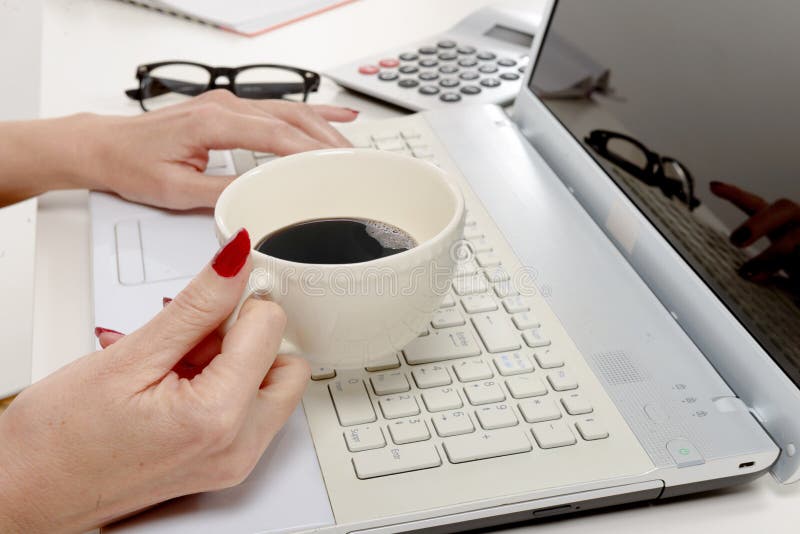 Mano de la mujer con la taza de café en el escritorio foto de archivo libre de regalías Mano de la mujer con la taza de café en el escritorio foto de archivo libre de regalías