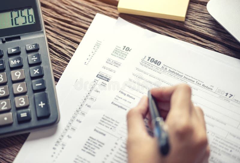 Mano de la mujer que escribe U S forma de impuesto 1040, usando declaraci?n sobre la renta individual de la calculadora, impuesto fotografía de archivo libre de regalías Mano de la mujer que escribe U S forma de impuesto 1040, usando declaraci?n sobre la renta individual de la calculadora, impuesto fotografía de archivo libre de regalías