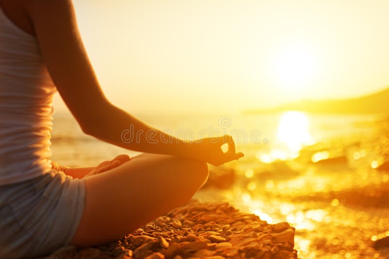 Mano de la mujer que medita en una actitud de la yoga en la playa